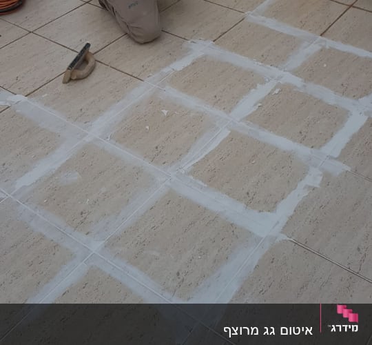 אדם מורח חומר איטום על רצפת אריחים